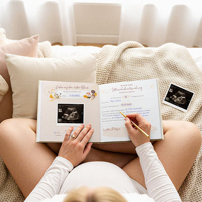 Schwangere Frau füllt das Eulentaler Schwangerschaftstagebuch mit Ultraschallbildern und persönlichen Erinnerungen zur Schwangerschaft aus.
