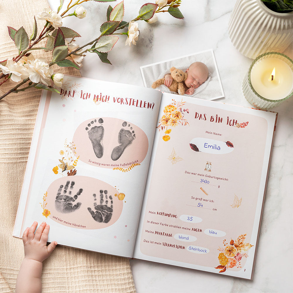 Geöffnetes Eulentaler Babyalbum „Mein erstes Jahr“ in Rosa mit Hand- und Fußabdrücken, persönlichen Geburtsdaten und liebevoll gestalteten Erinnerungsseiten.
