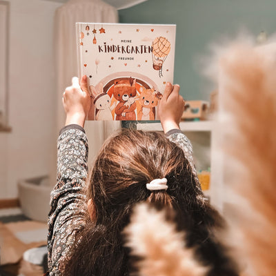 Mädchen füllt das Eulentaler Freundebuch „Meine Kindergartenfreunde“ mit Einhorn-, Feen- und Blumenmotiven aus.
