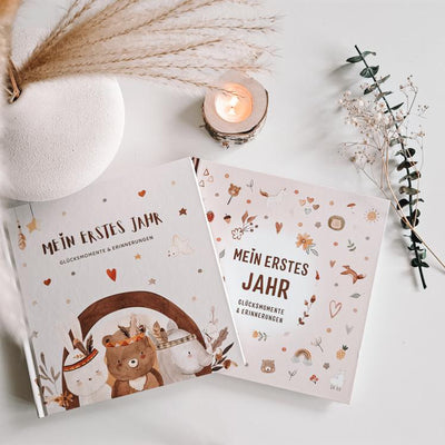 Eulentaler Babyalbum „Mein erstes Jahr – Glücksmomente & Erinnerungen“ im Boho-Design mit liebevoll illustriertem Cover neben Kerze und Trockenblumen.
