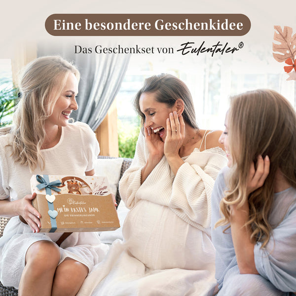 Schwangere Frau freut sich mit zwei Freundinnen über die Eulentaler Erinnerungsbox „Mein erstes Jahr“ als Geschenk zur Geburt.
