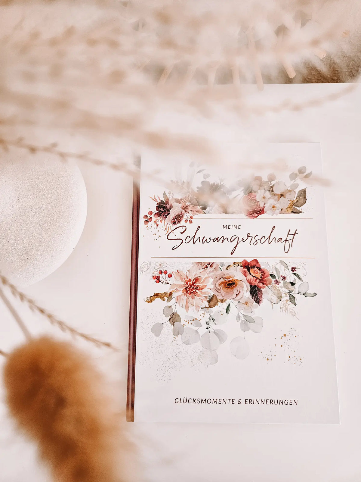 Detailansicht eines edel gestalteten Schwangerschaftstagebuchs mit floralen Elementen auf dem Cover.